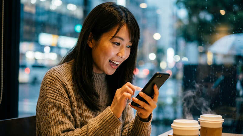 スマホ画面を見ながら楽しそうに笑う女性のイメージ